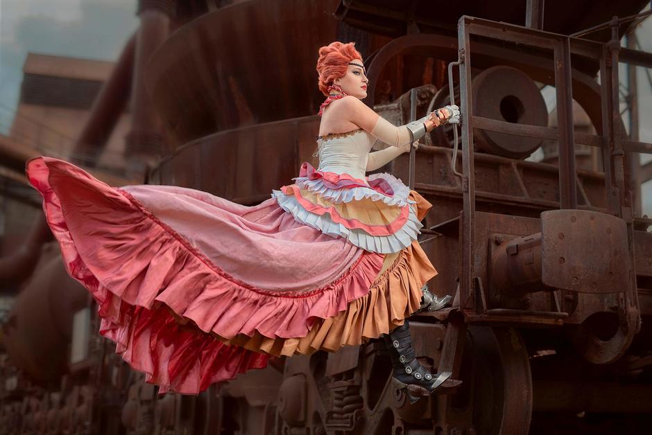 Steampunková móda se setkává s industriálním dědictvím: volánkové šaty v korálových tónech.